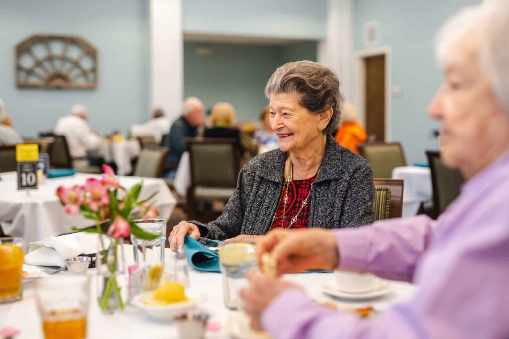 Smiling senior women seated at dining table in community dining room