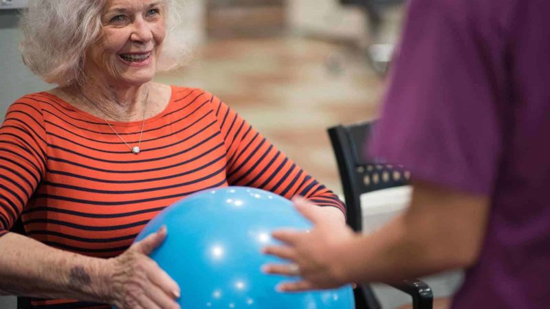 Senior woman holding medicine ball during therapy activity